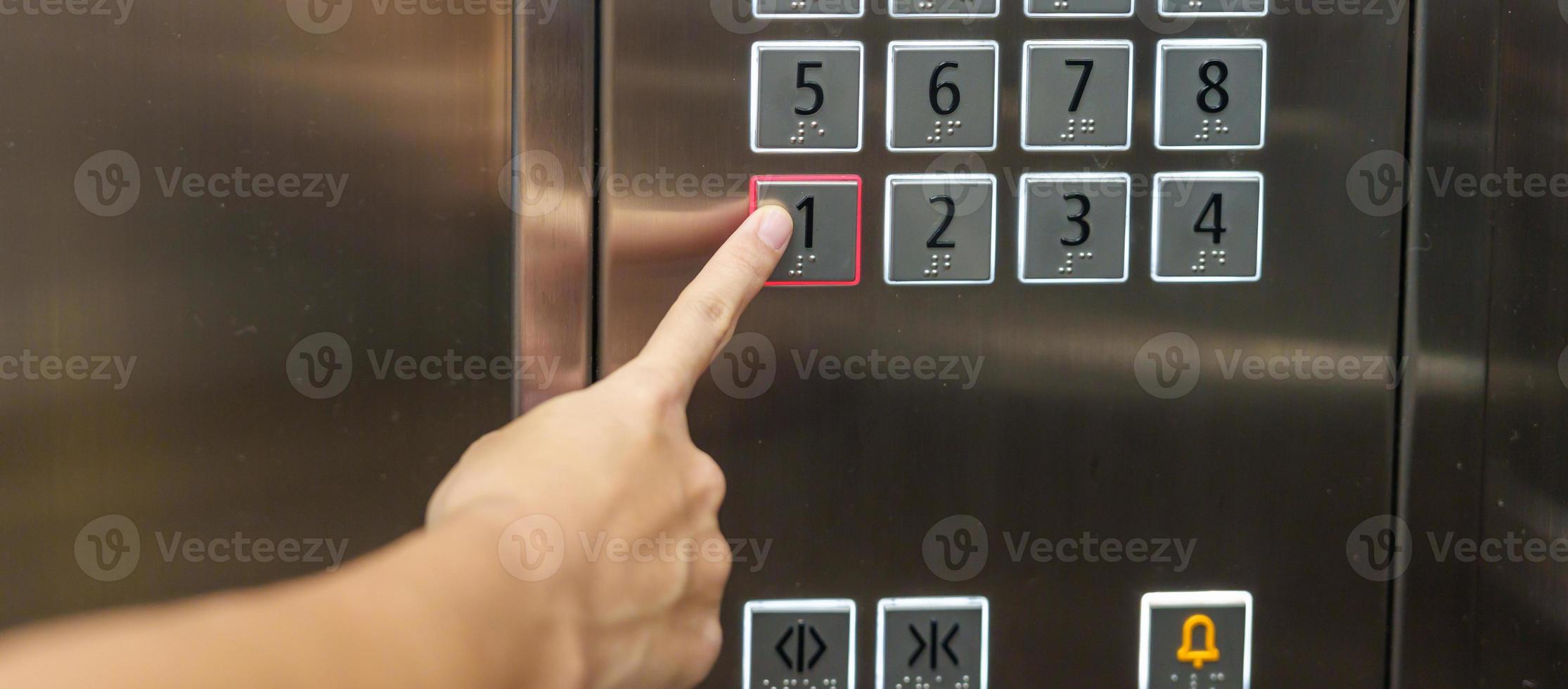el dedo de la mano presiona el botón del ascensor, la mujer que usa el ascensor en la oficina o el apartamento foto