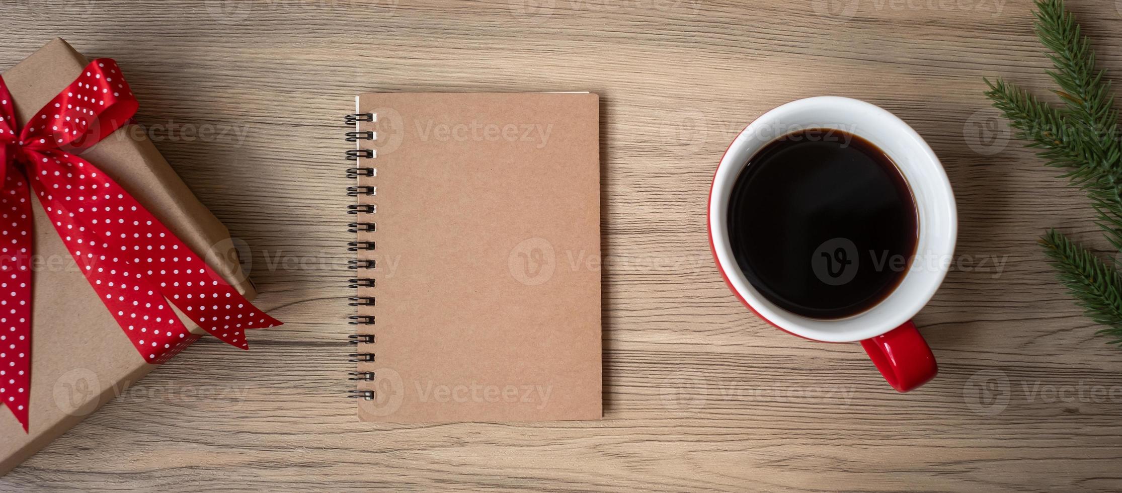 Blank notebook, black coffee cup and Christmas gift on wood table, Top view and copy space. Xmas, Happy New Year, Goals, Resolution, To do list, Strategy and Plan concept photo