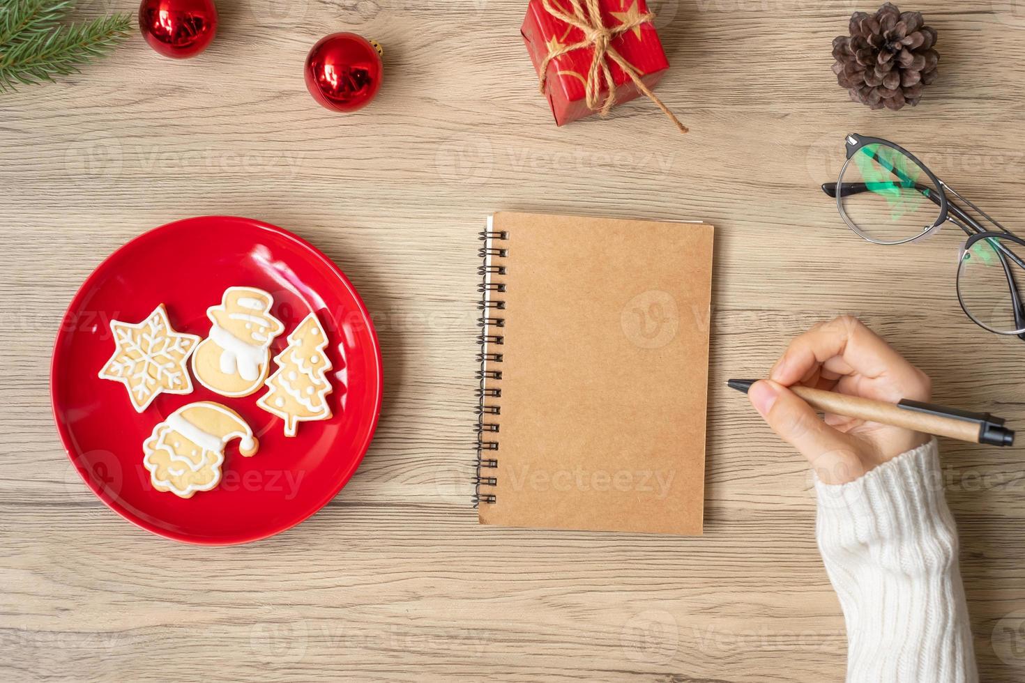 Woman hand writing on notebook with Christmas cookies on table. Xmas, Happy New Year, Goals, Resolution, To do list, Strategy and Plan concept photo