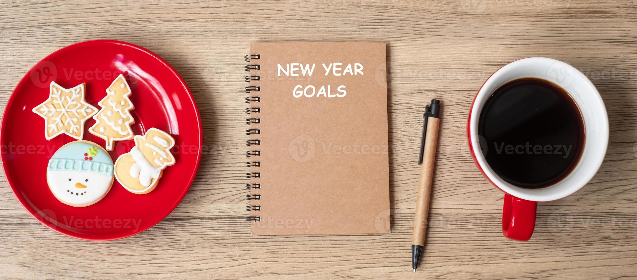 New Year Goal with notebook, black coffee cup, Christmas cookies and pen on wood table.  Xmas, Happy New Year, Resolution, To do list, Strategy and Plan concept photo