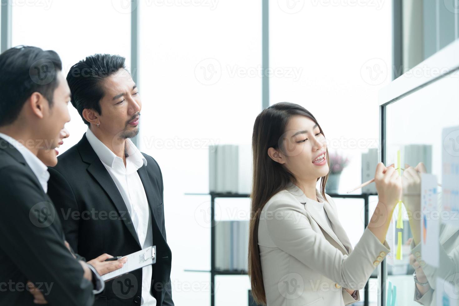 jóvenes empresarios en asia organizan reuniones para generar ideas y revisar información en tableros de vidrio foto