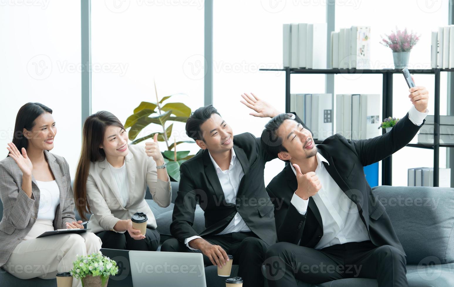 jóvenes empresarios en asia toman un descanso para relajarse en la sala de relajación después de una reunión. viendo películas, tomando fotos