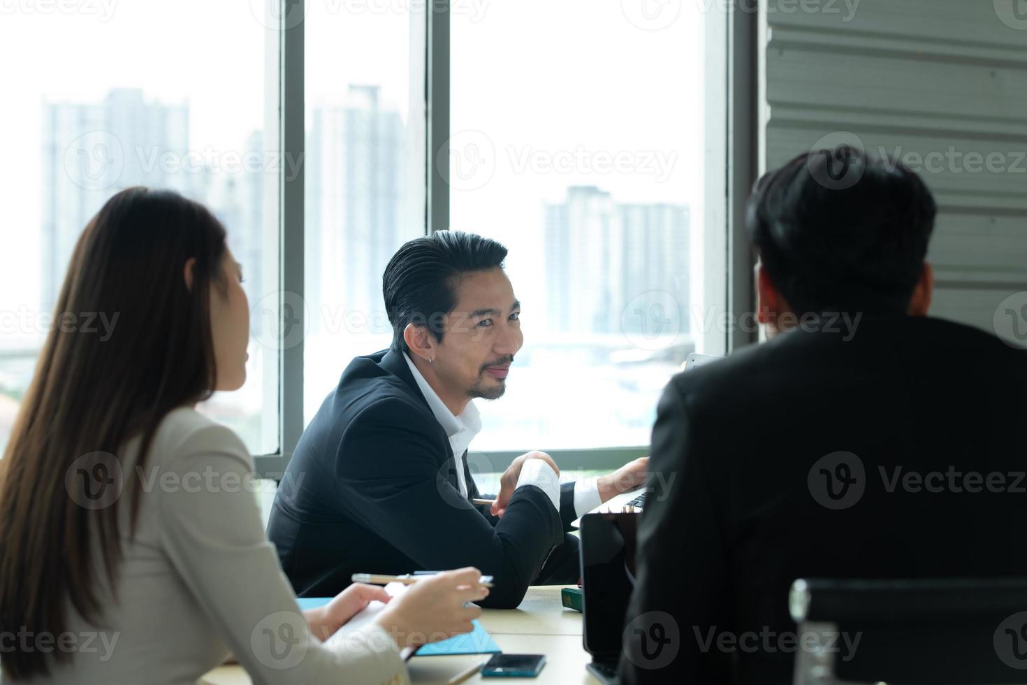 A group of young Asian entrepreneurs. Top Management is meeting to review stock investment data from the team in a meeting room with natural light photo