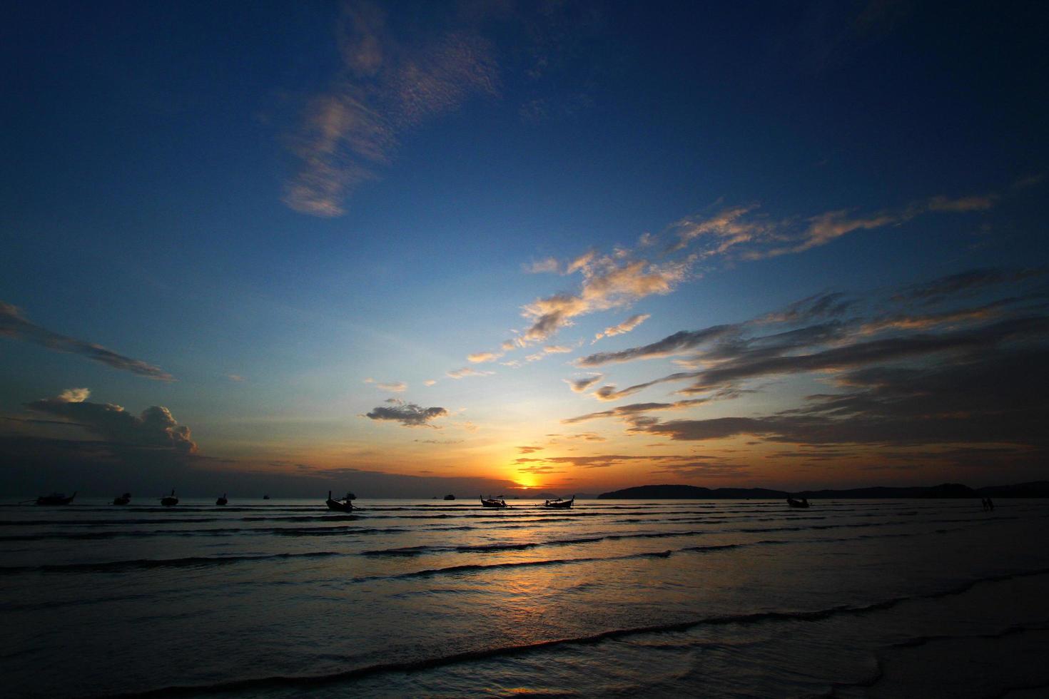 silueta de barco y bote de cola larga en el mar o el océano con cielo azul y nubes al atardecer, amanecer o crepúsculo en krabi, tailandia. belleza en la naturaleza con concepto de onda y transporte foto