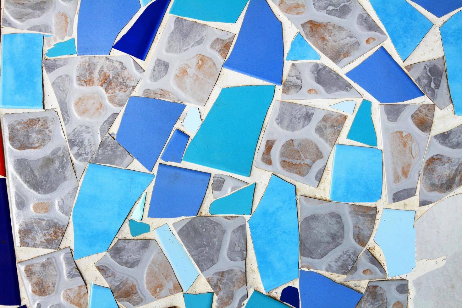 colorido del suelo de baldosas de mosaico para el fondo. papel pintado de diseño de arte, agrietado, forma y abstracto. fragmentos de azulejos azules, grises o grises y blancos en la pared. foto