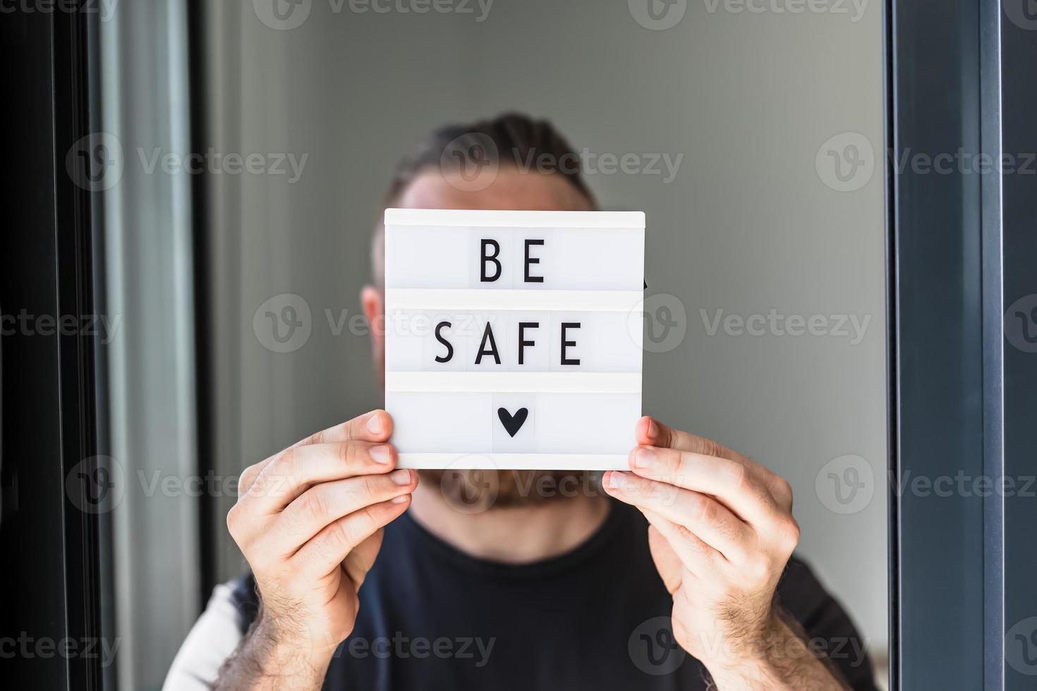 Man holding lightbox with text Be safe in his hand photo