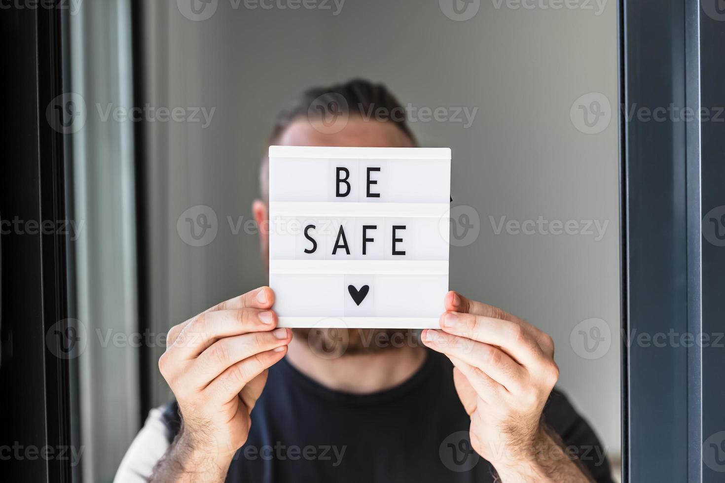 hombre sosteniendo una caja de luz con el texto esté seguro en su mano foto