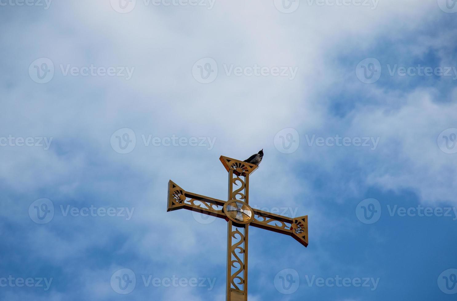 cruz de la iglesia ortodoxa contra el cielo azul. una golondrina se sienta en una cruz. concepto de pascua foto