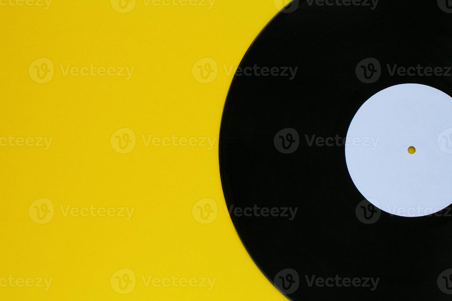 Close up of black old vinyl record play disc vintage on a yellow background with copy space for text. Retro LP history, nostalgia concept. Sound technology for DJ to mix music. Flat lay, top view photo