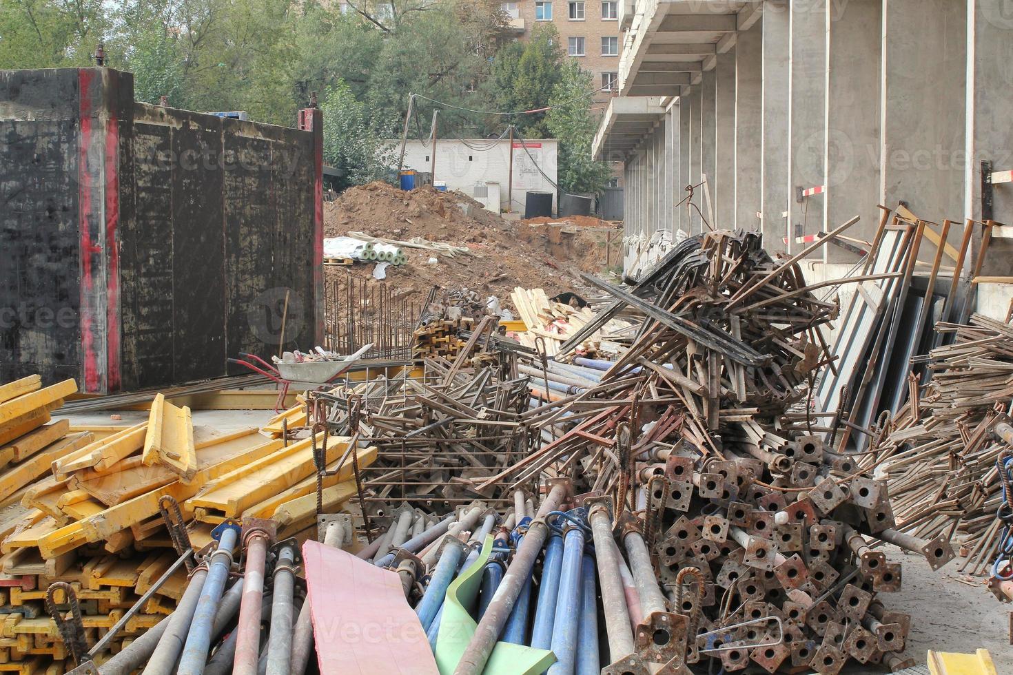 Pile of metal pipeline construction materials, iron profiles, steel rods for scaffolding on a building site. Renovation, planning, repair modern civil house. Concept of development improvement town photo