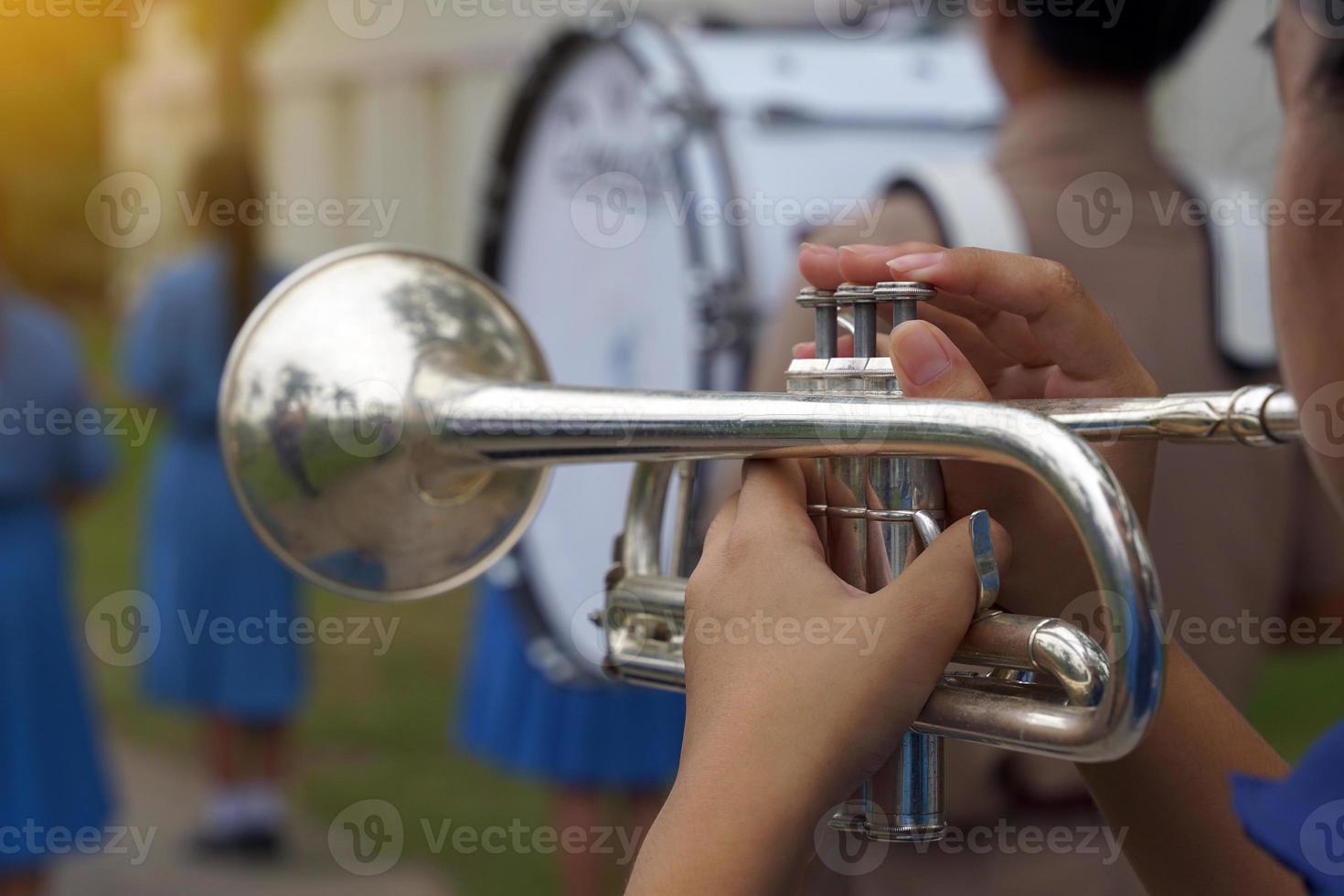 rlose-up of student's hand pressing the button of a trumpet to chase a musical note, playing a song while practicing for a school parade. Soft and selective focus. photo