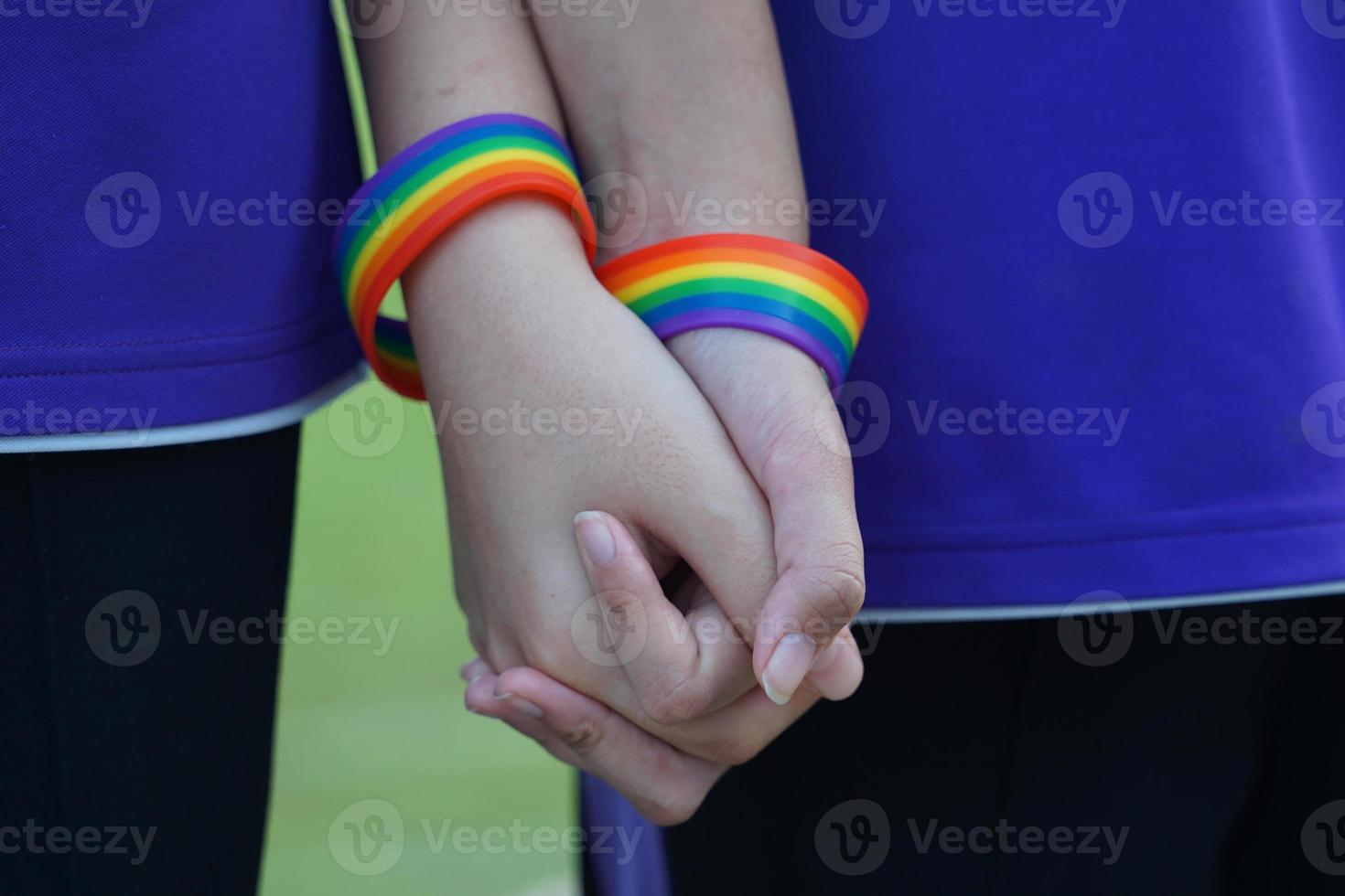 LGBT Asian youth couple wearing rainbow wristbands held together to show their love. Pride of being LGBT. soft and selective focus. photo