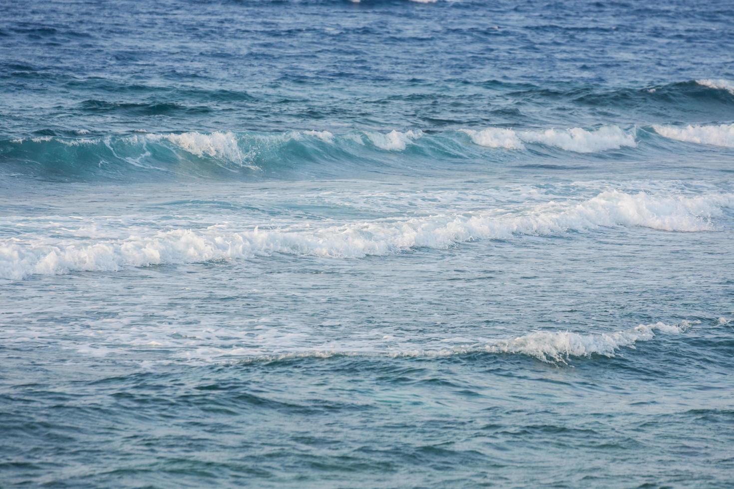 olas altas en una playa con agua de mar azul foto