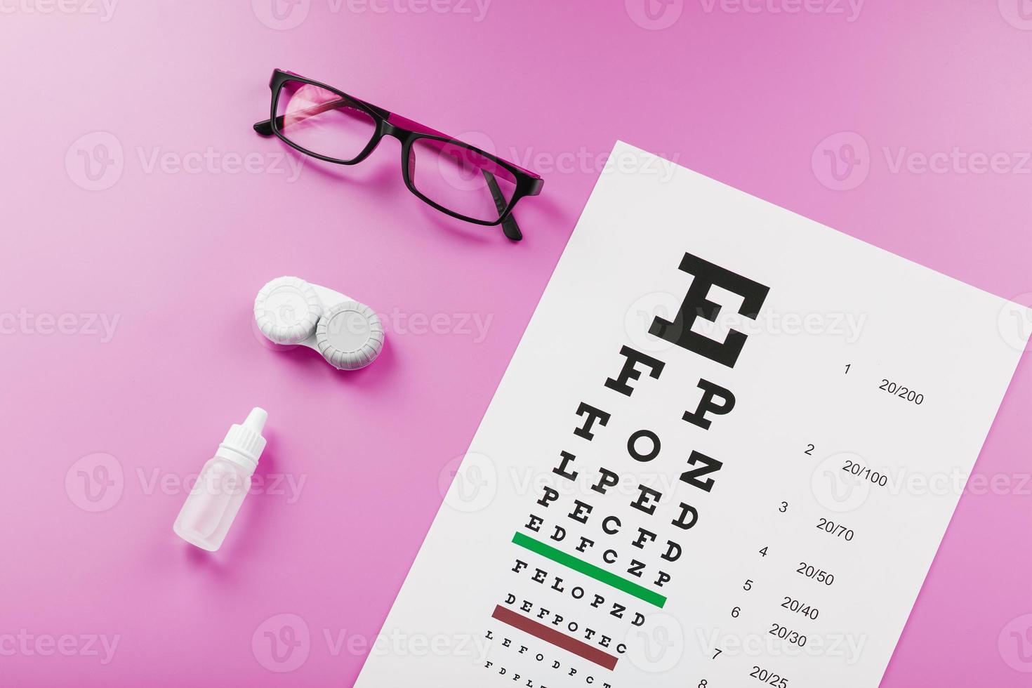 accesorios oftálmicos anteojos y lentes con mesa de prueba de visión para la corrección de la visión sobre un fondo rosa. foto