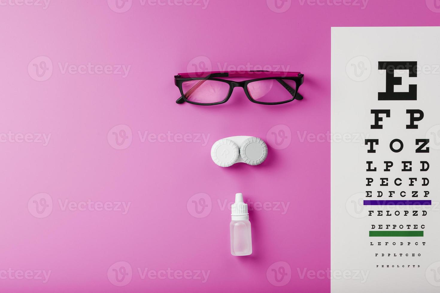 Ophthalmologist accessories glasses, lenses and vitamins with a test target for vision correction on a pink background. photo