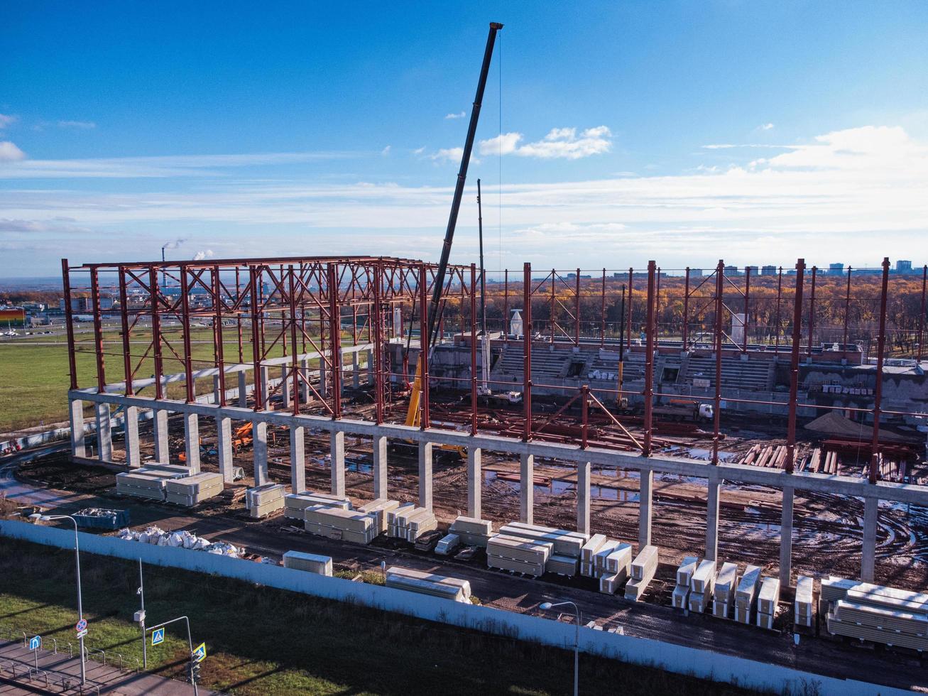 Construction cranes lift the beams of the metal frame of the building onto a concrete base. photo