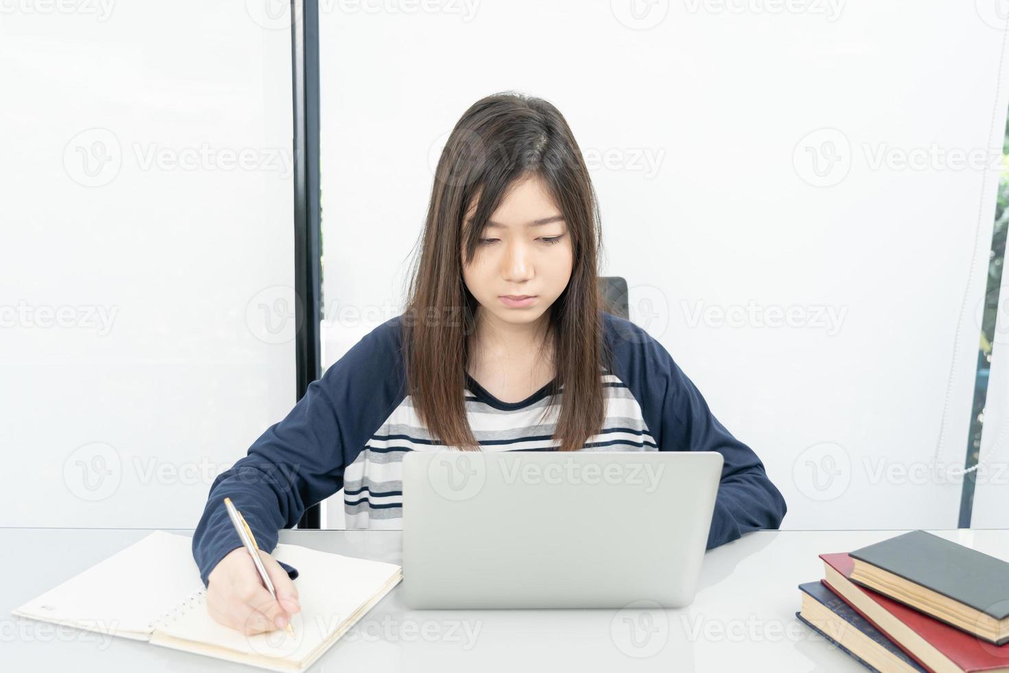 Young female student  sitting in living room and learning online photo