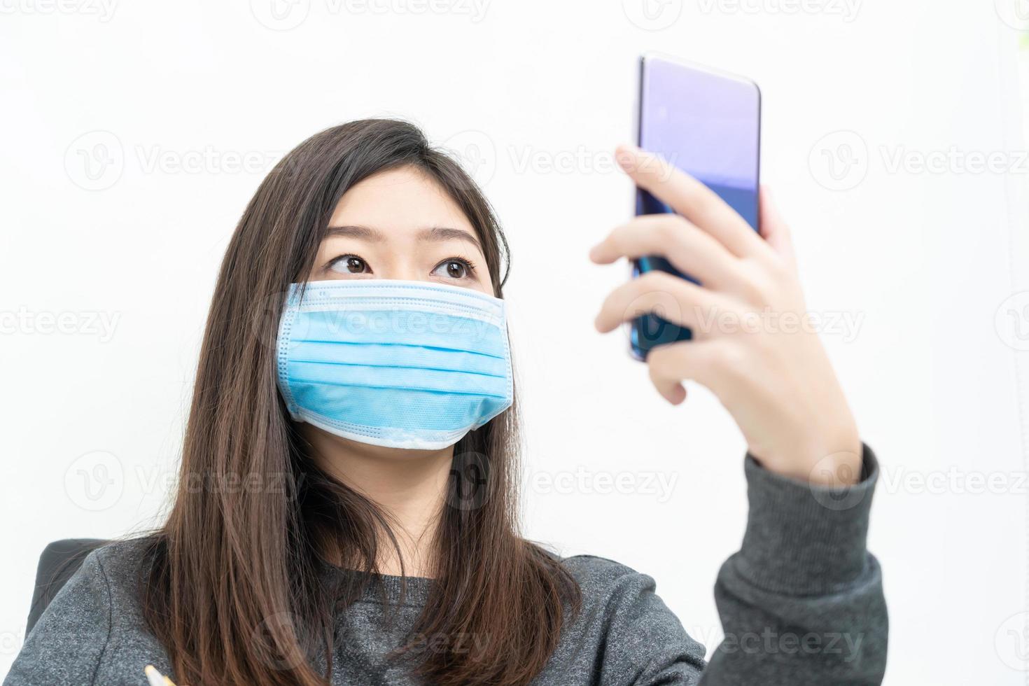 Woman long hair wearing protective mask holding and using mobile phone photo