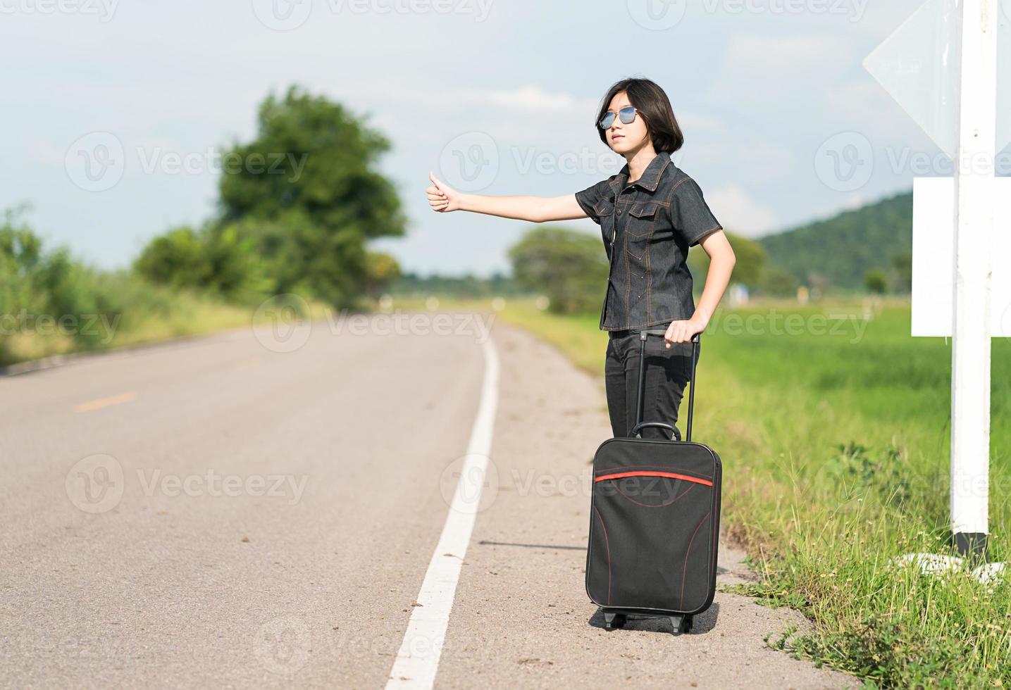 Woman short hair with luggage hitchhiking and thumbs up photo