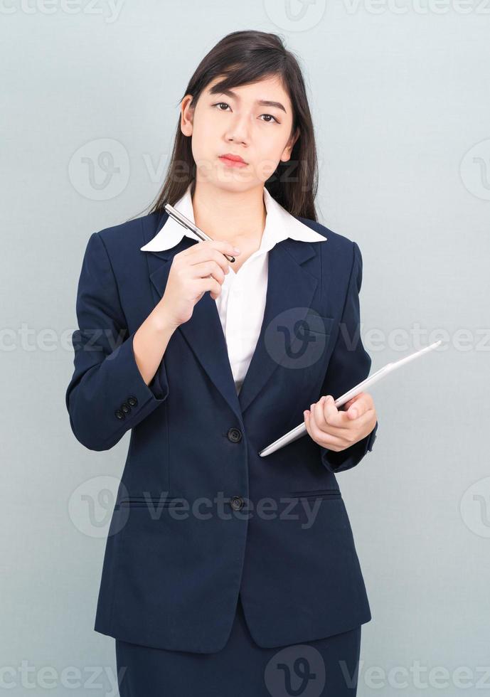 mujer en traje usando tableta digital sobre fondo gris foto