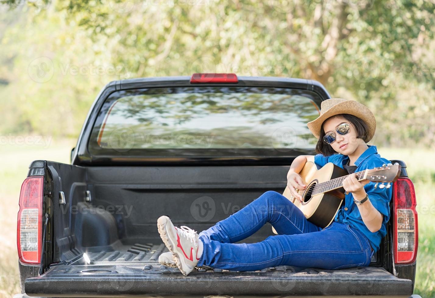 mujer usa sombrero y toca la guitarra en una camioneta foto