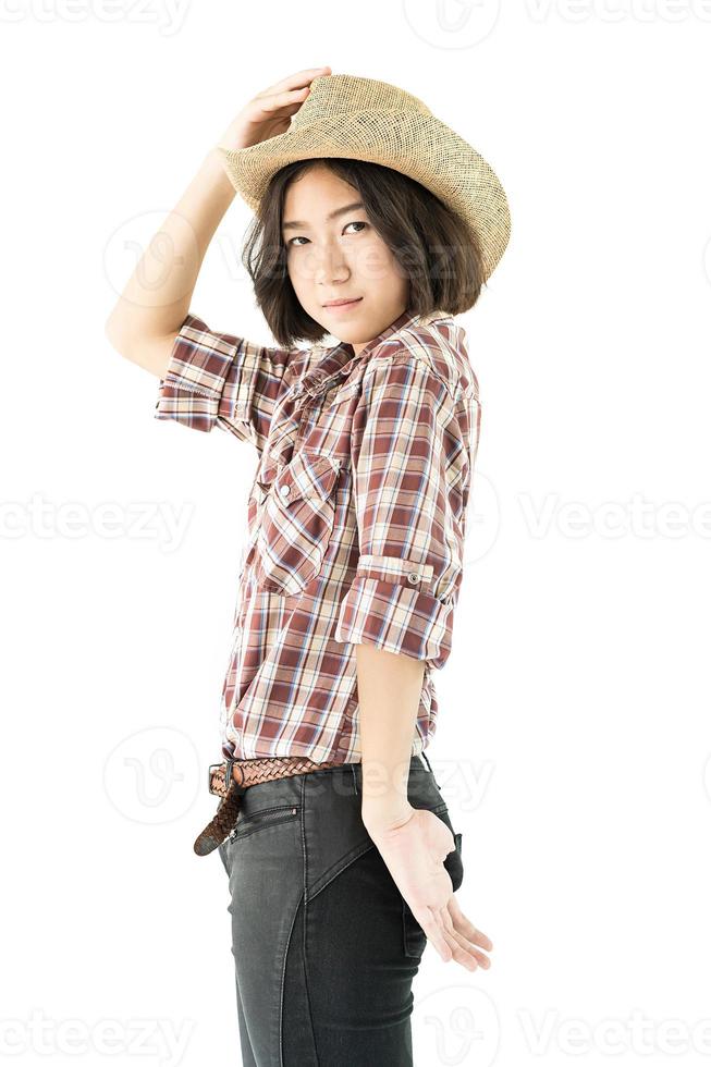 Young woman in a cowboy hat and plaid shirt with hand on her hat photo