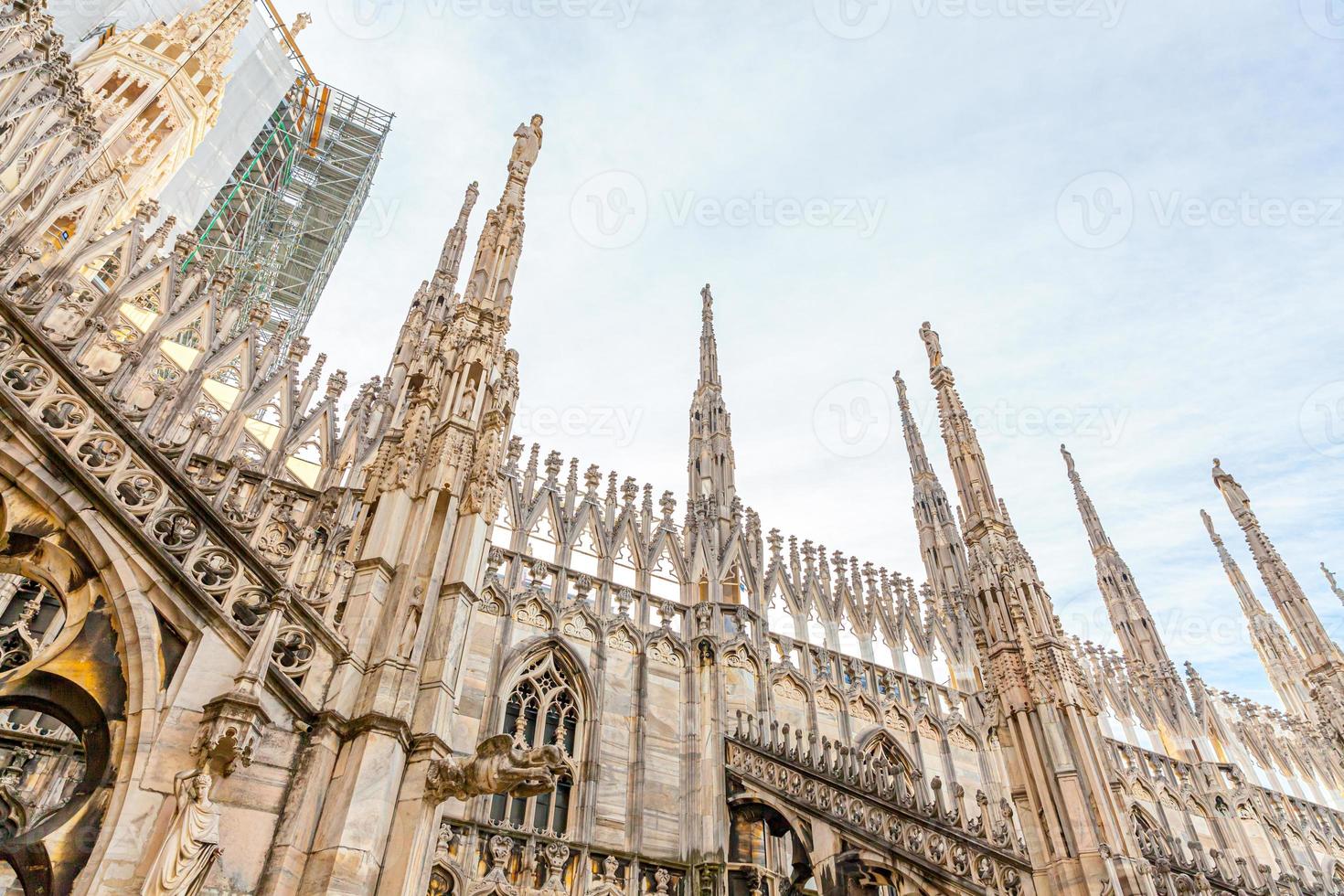 Roof of Milan Cathedral Duomo di Milano with Gothic spires and white marble statues. Top tourist attraction on piazza in Milan, Lombardia, Italy. Wide angle view of old Gothic architecture and art. photo