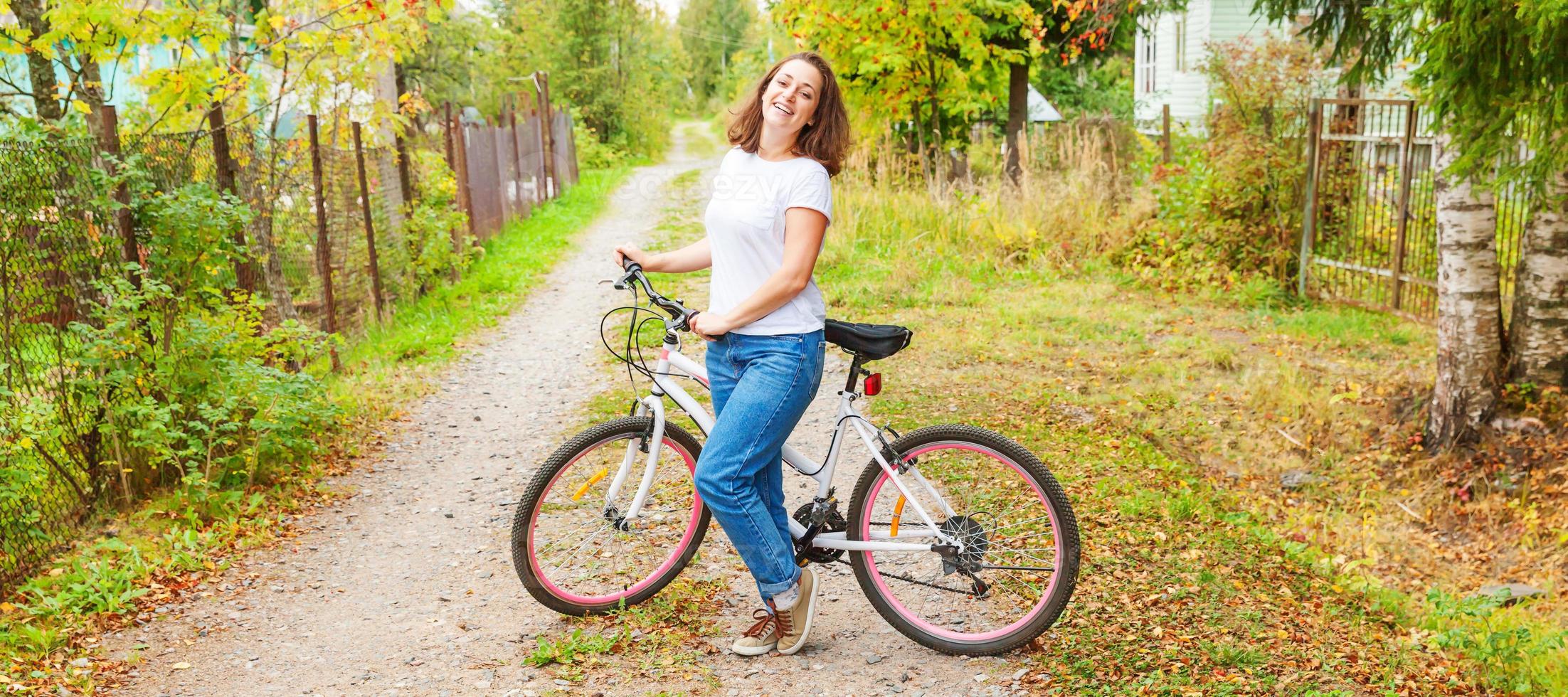 mujer joven montando en bicicleta en el parque de la ciudad de verano al aire libre. gente activa chica hipster relajarse y andar en bicicleta. ir en bicicleta al trabajo en el día de verano. concepto de estilo de vida de bicicleta y ecología. foto