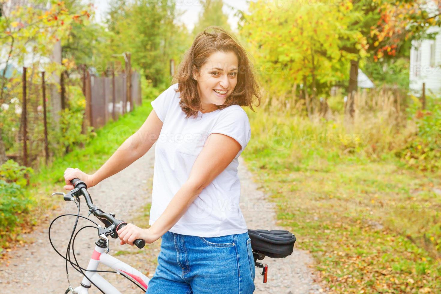 mujer joven montando en bicicleta en el parque de la ciudad de verano al aire libre. gente activa chica hipster relajarse y andar en bicicleta. ir en bicicleta al trabajo en el día de verano. concepto de estilo de vida de bicicleta y ecología. foto