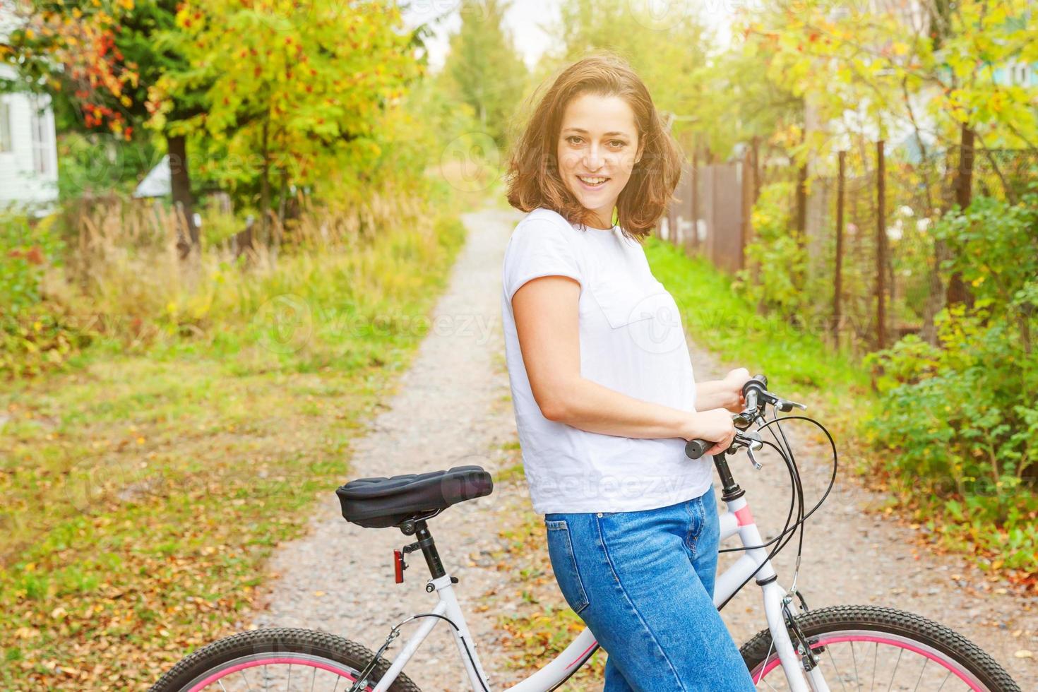 Young woman riding bicycle in summer city park outdoors. Active people. Hipster girl relax and rider bike. Cycling to work at summer day. Bicycle and ecology lifestyle concept. photo