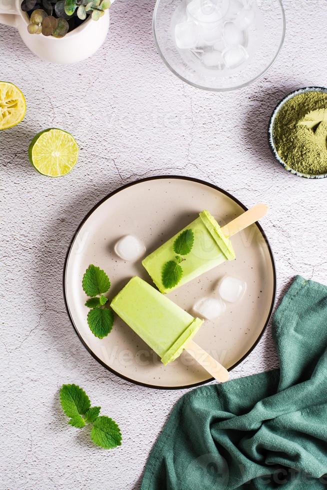 Vegetarian popsicle made from matcha tea, coconut milk and mint on a plate. Top and vertical view. photo