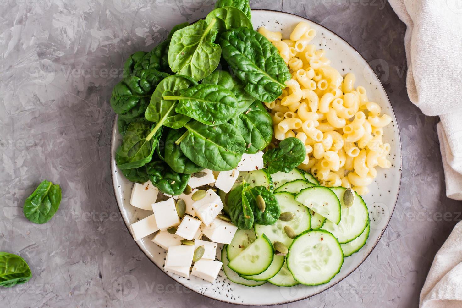 Bowl with pasta, cucumber, cheese and spinach on the table.  Top view. Close-up photo