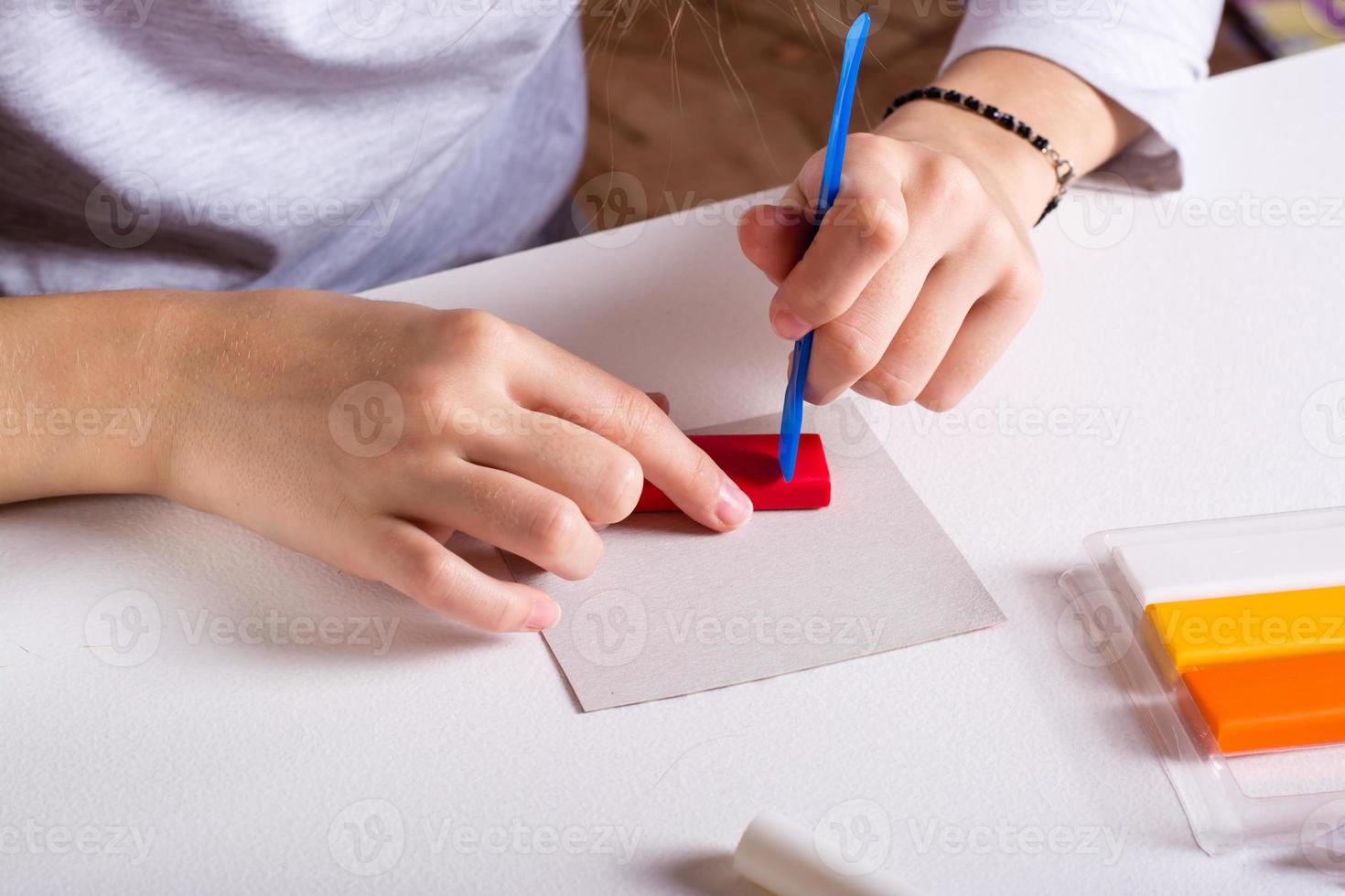 Children's hands cut polymer clay with a modeling tool. Handmade and leisure. photo