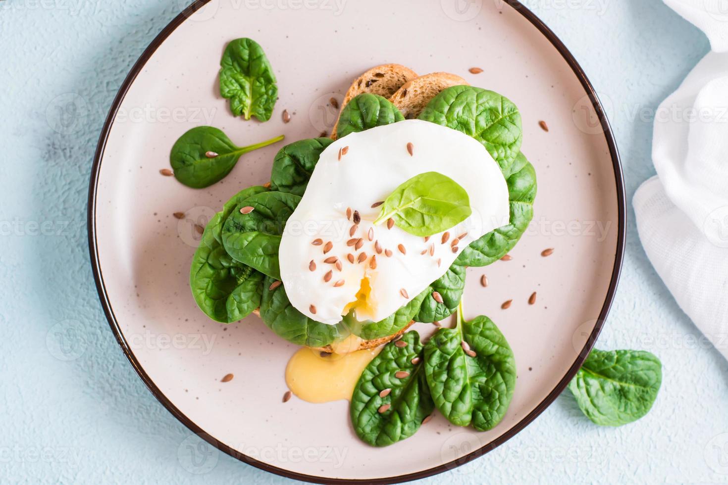 Appetizing sandwich with poached egg and spinach on a plate. Flexetarian Diet. Top view. Close-up photo