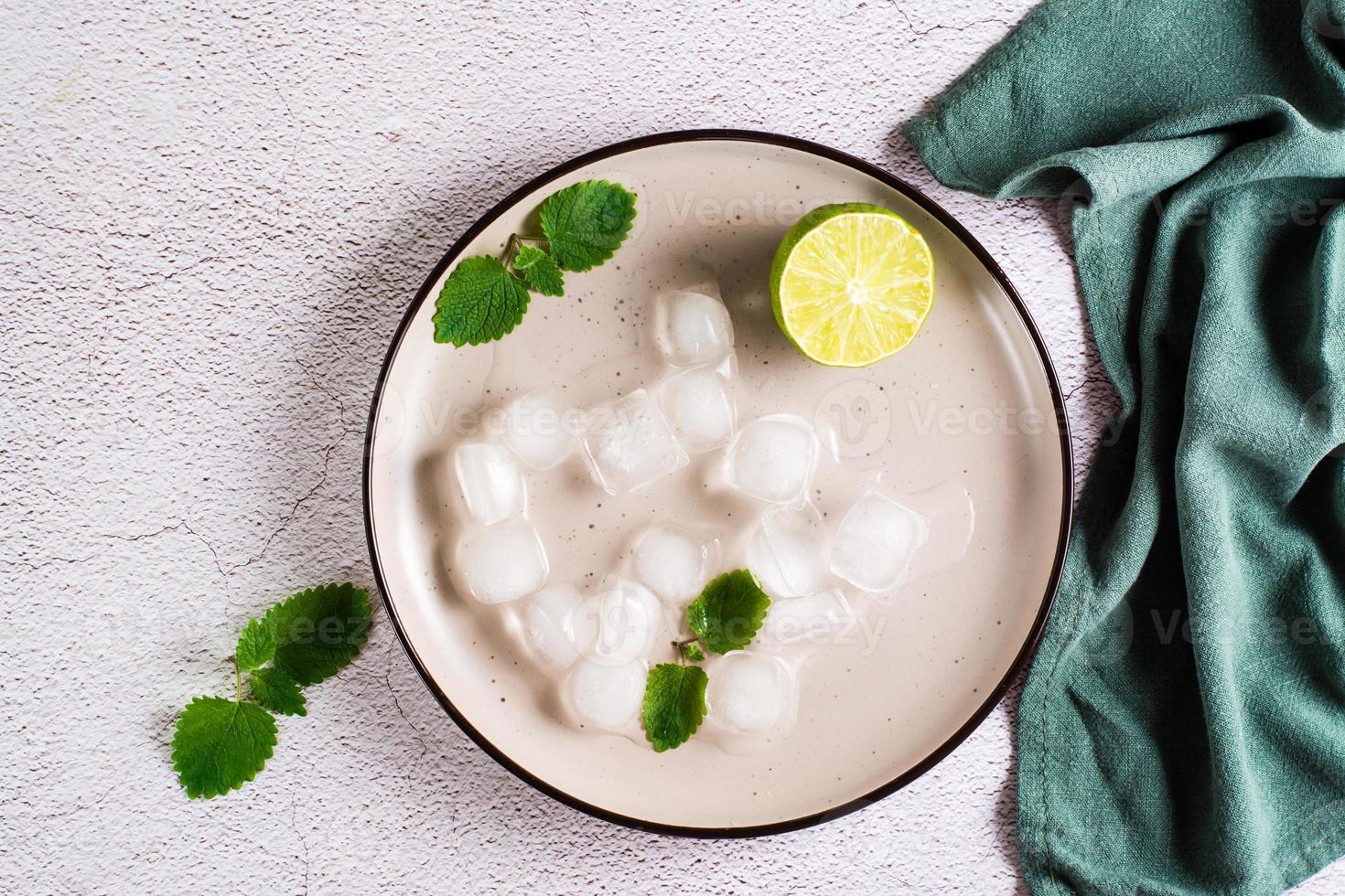 Melted ice cubes, lime and mint leaves on a plate on the table. Home made cocktails. Top view photo