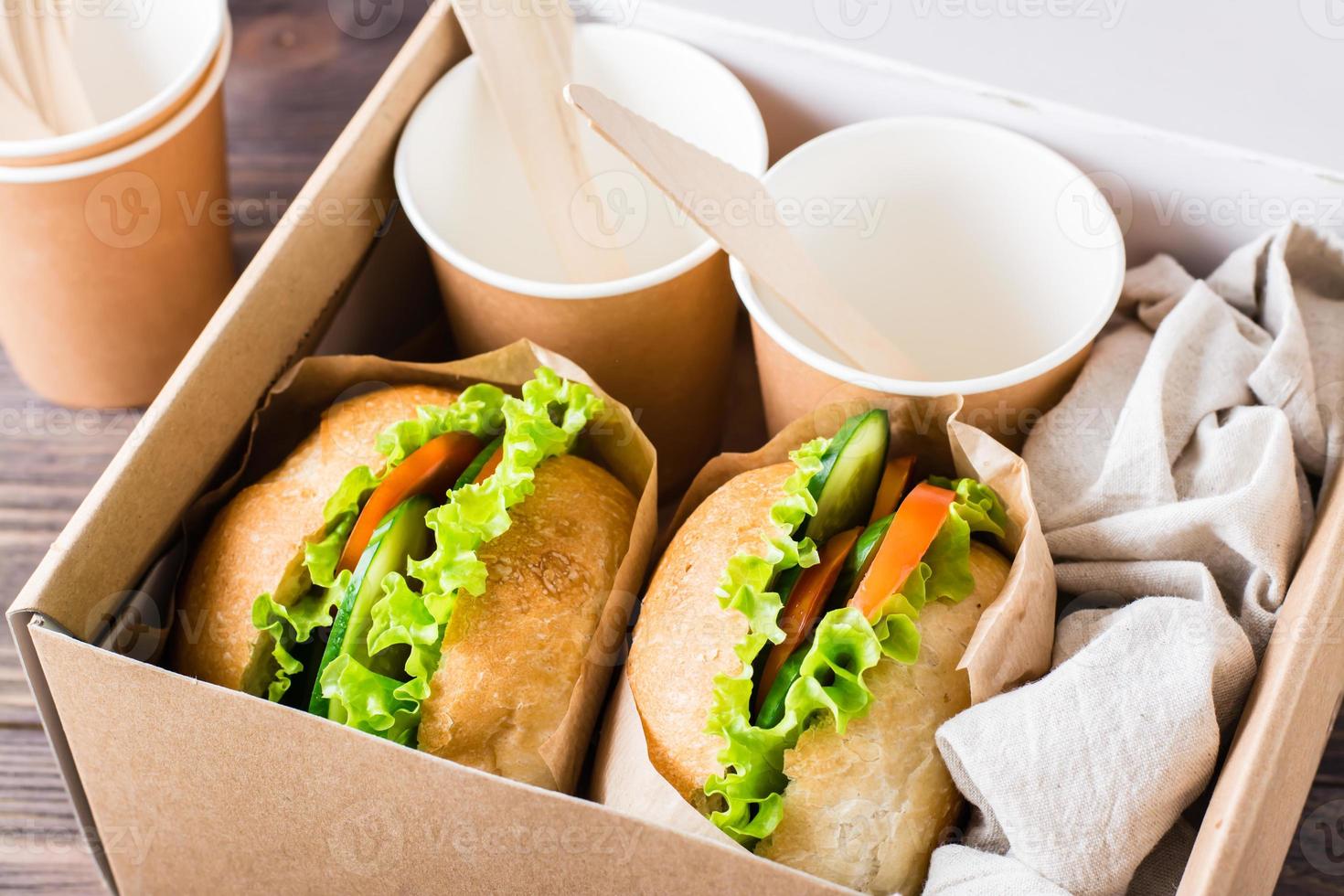 Vegetarian burgers with fresh vegetables and lettuce in a bun in a box. Fast food delivery. photo