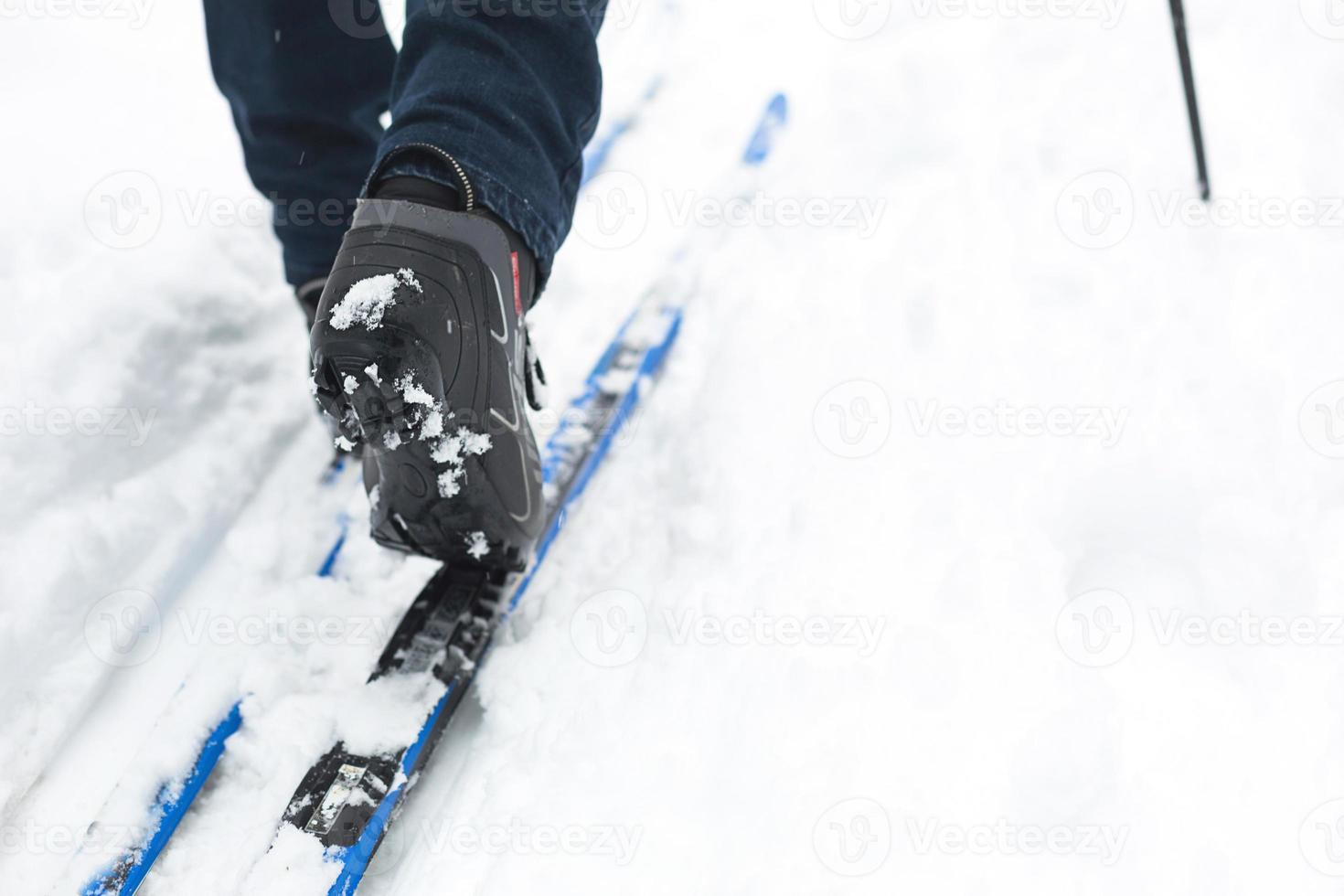 Feet of a skier in ski boots on cross-country skis. Walking in the snow, winter sports, healthy lifestyle. Close-up, copyspace photo