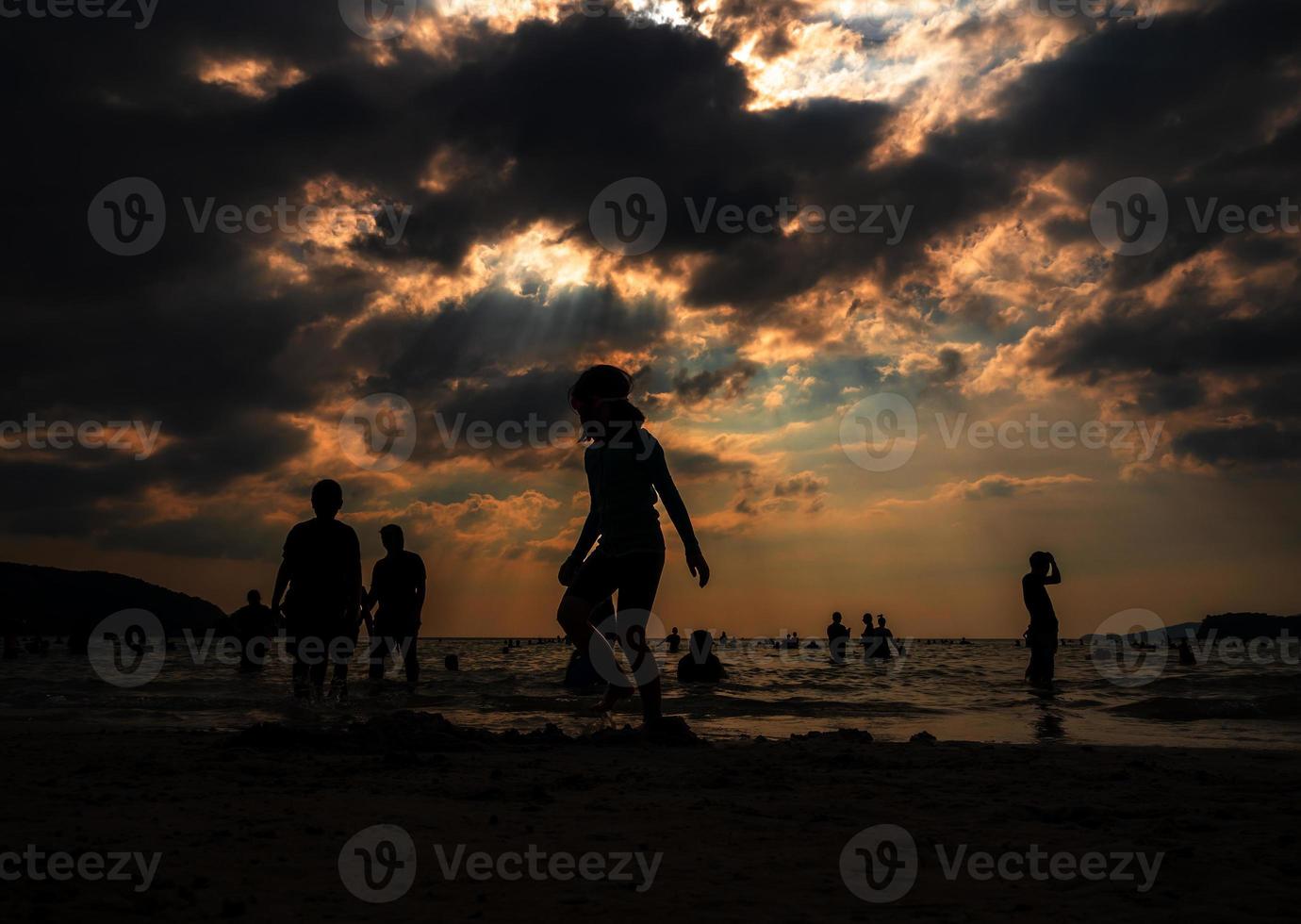 Silhouettes of people playing in the sea at a public beach photo