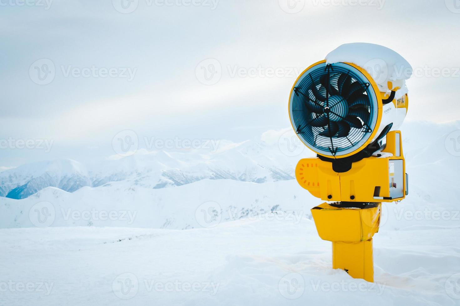 Yellow snow cannon under snow in Gudauri ski resort in snowy mountains after fresh snow fall. Good snow situation and fake snow technology photo