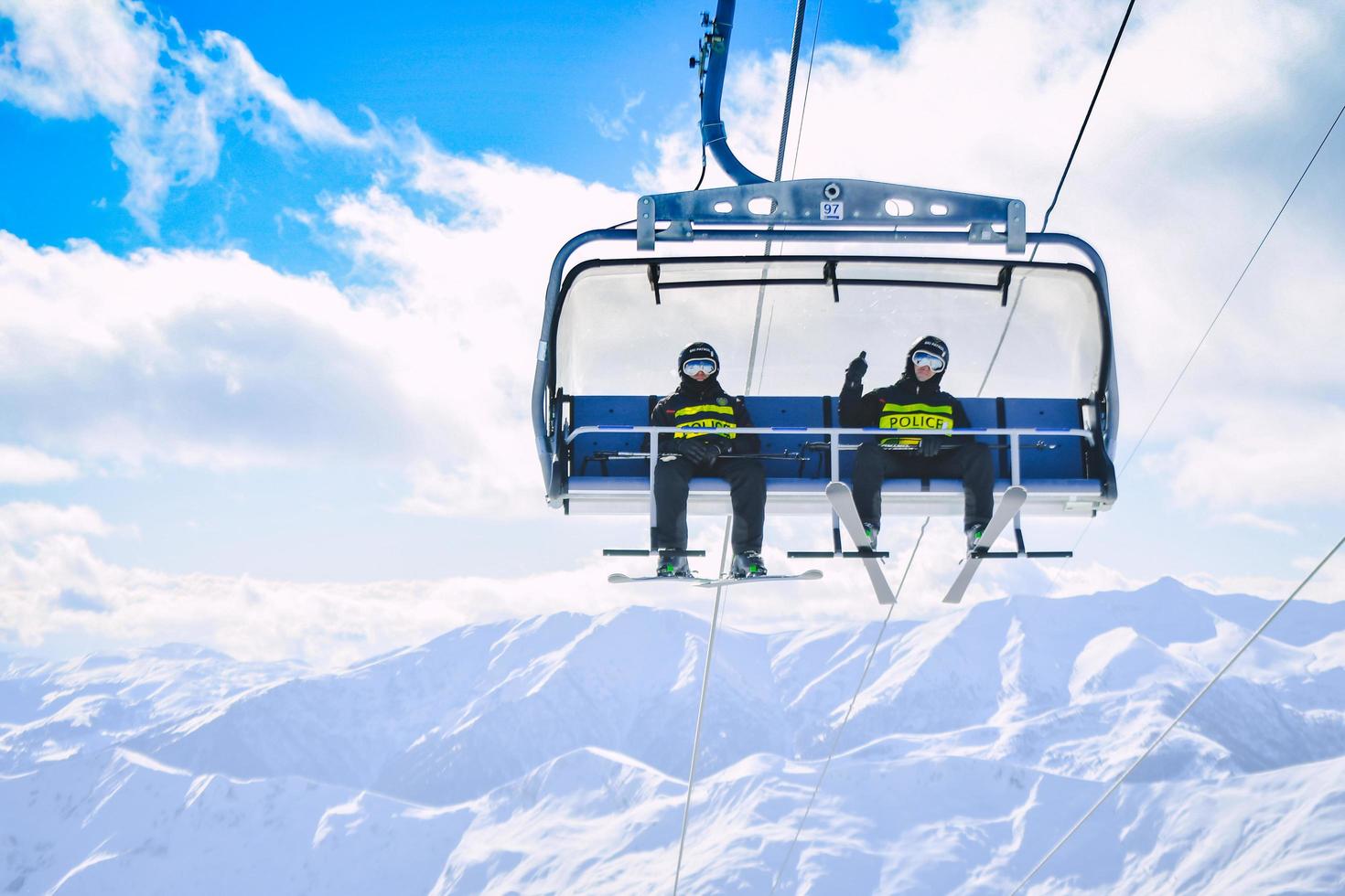 gudauri, georgia, 2022 - dos esquiadores de la patrulla de la policía se sientan y muestran los pulgares hacia arriba en el remonte en la estación de esquí de gudauri. seguridad y asistencia de emergencia en las montañas foto