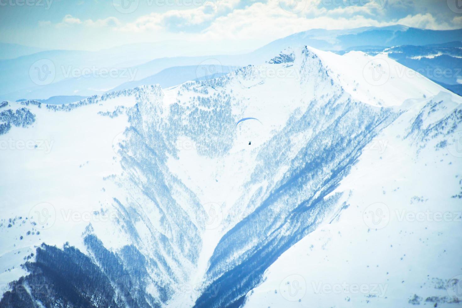 People paragliding tandem above mountain in winter in Georgia ski resort. Concept of active lifestyle and extreme sport adventure. photo