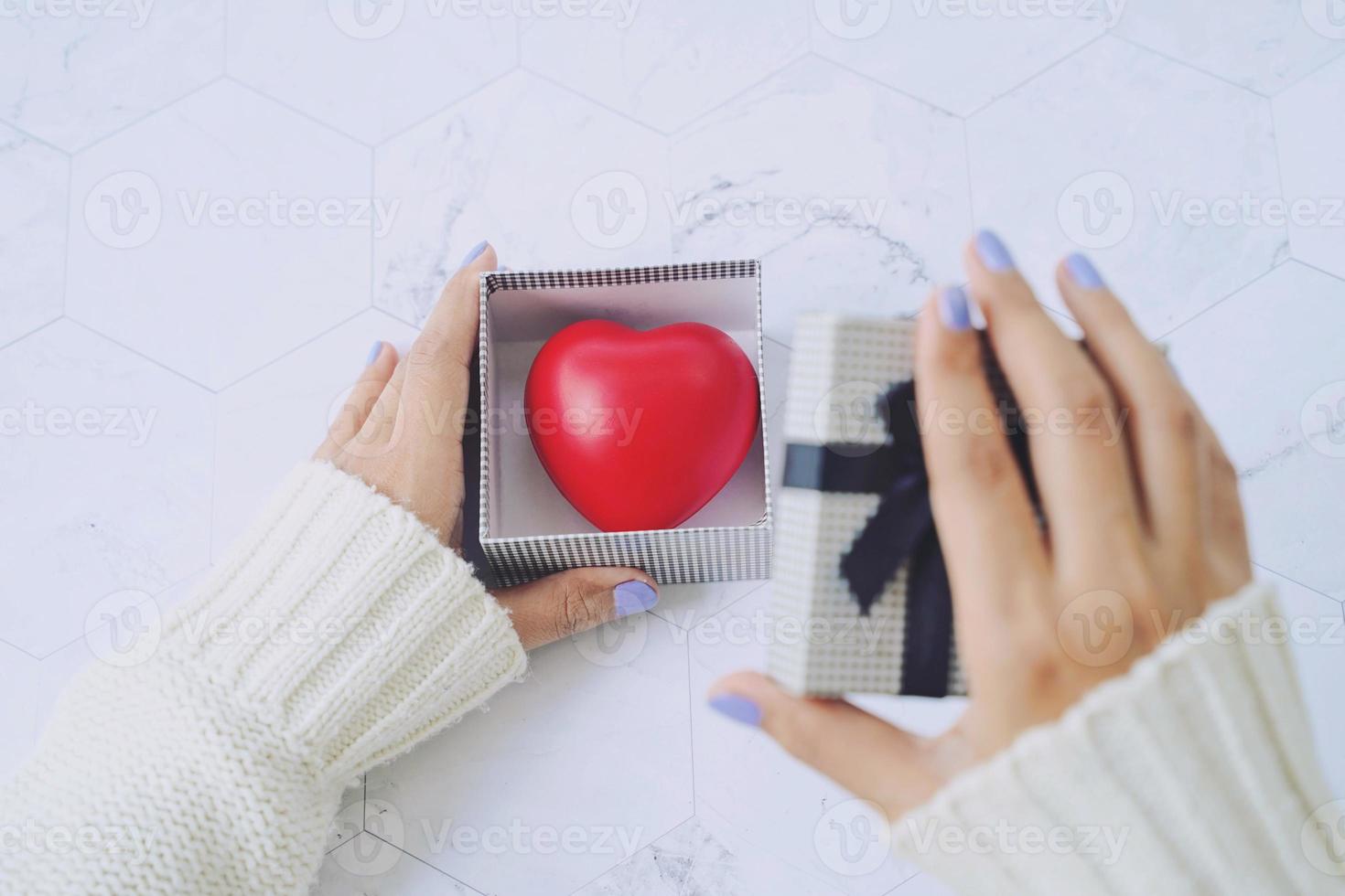 Top view of woman hands open gift box and red heart inside the present, love and holiday concept photo