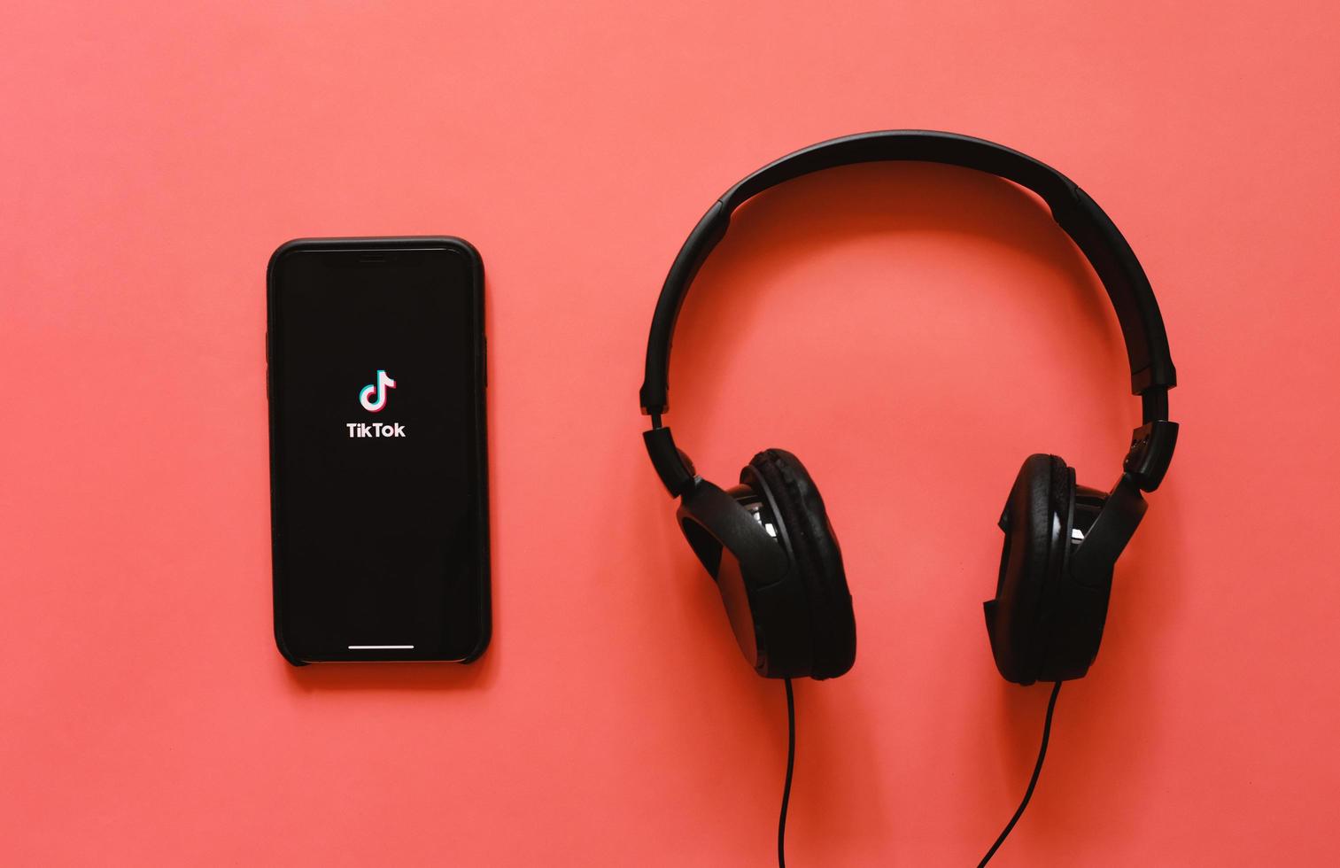 Flat lay of iPhone XS showing Tik Tok application on screen with headphone, Tik tok is popular social media network and entertainment photo