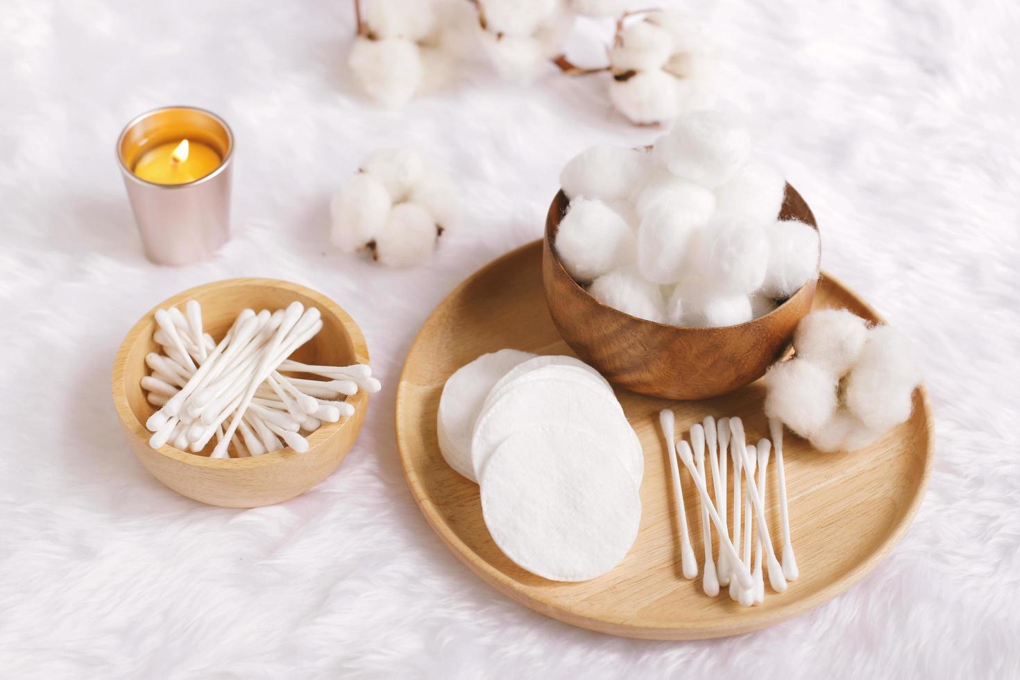 Organic cotton facial pads, cotton balls and cotton buds for removal makeup on wooden tray with natural cotton flowers on white fur background, hygiene and healthy care lifestyle photo