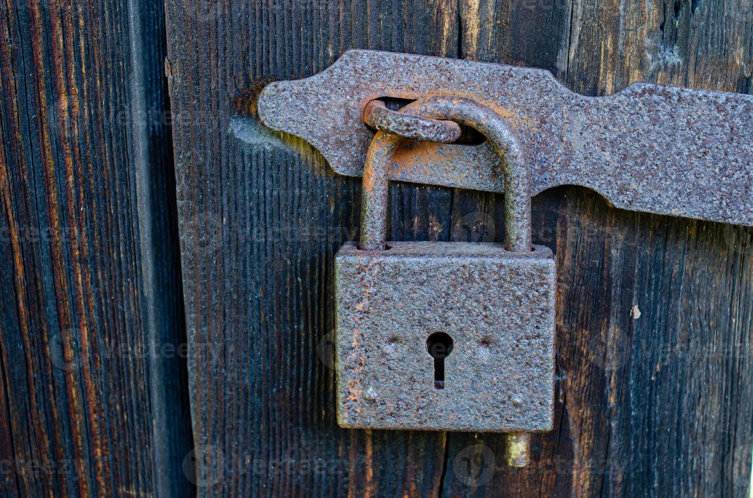 Lock on an old wooden door with rusty inserts photo