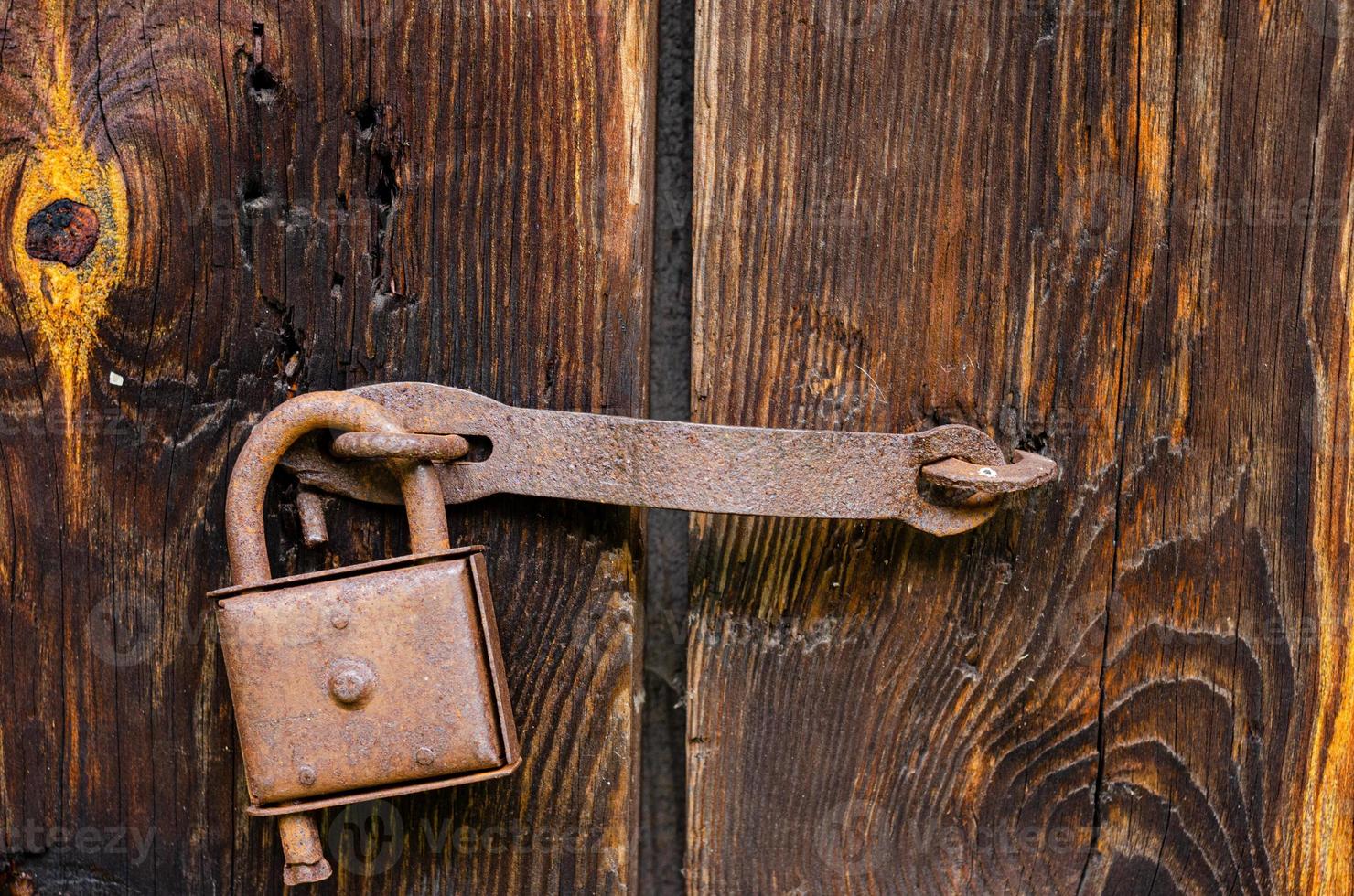 Lock on an old wooden door with rusty inserts photo