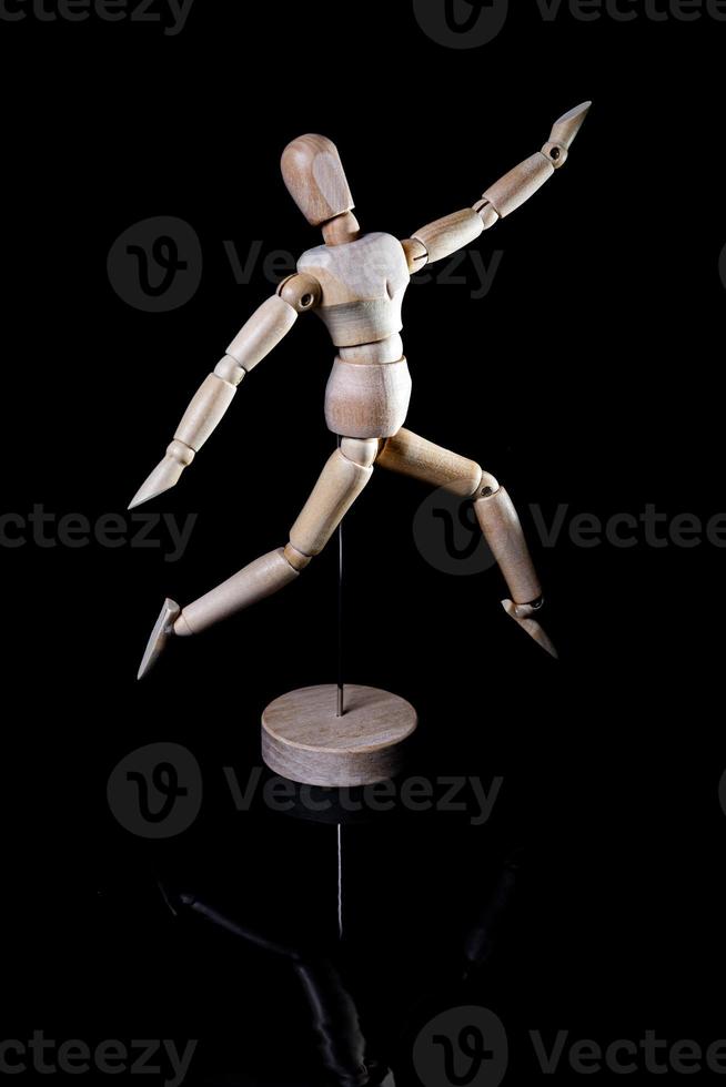 Image of wooden manikin on black background poses different posing photo