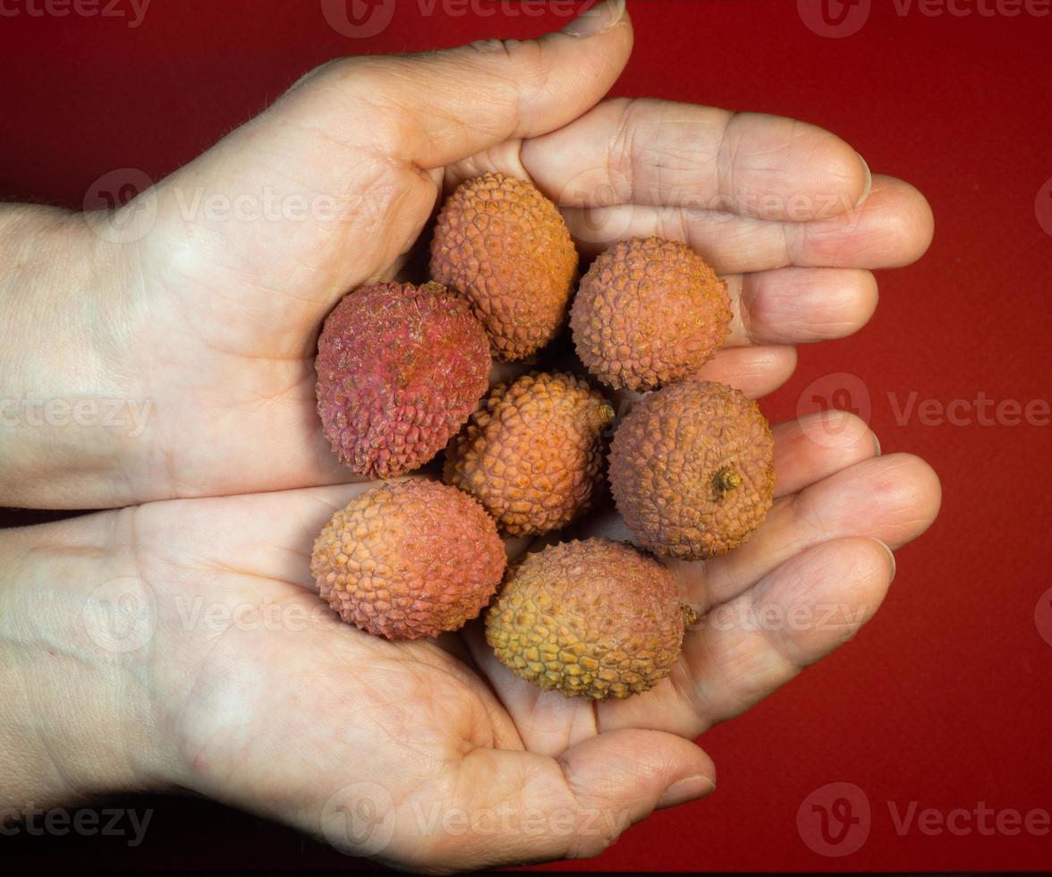 Lychee on the table. Chinese plum on a red background. Ripe fruit from Asia. Delicious, juicy product. Lychee pattern. photo