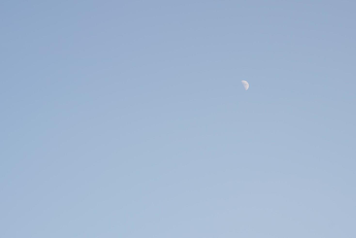 The moon rises during the day, the area is brightly colored. photo