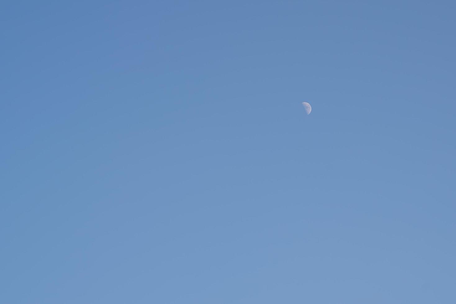 The moon rises during the day, the area is brightly colored. photo